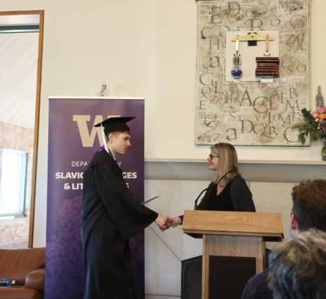 Anthony Veneziani in a cap and gown receiving his diploma.