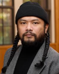 Garius wearing a beanie, golden earrings, and have pigtail braids, and just directly looking at the camera, pretending to be an author.